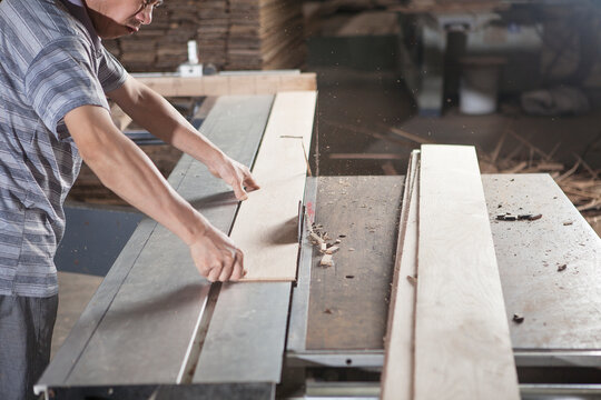 Carpenter working with wood plank in factory, Jiangsu, China