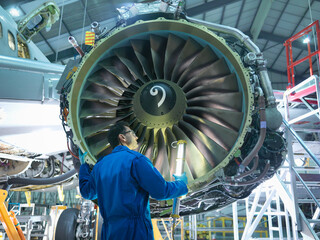 Engineer inspecting jet engine in aircraft maintenance factory © Image Source Limited