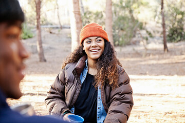 Young camping couple sitting in forest drinking coffee © Image Source Limited