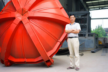 Worker standing beside part in crane manufacturing facility, China
