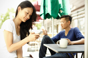 Tourist couple at sidewalk cafe using smartphones, The Bund, Shanghai, China