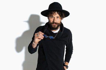 fashion model removing his sunglasses, holding one hand in pocket