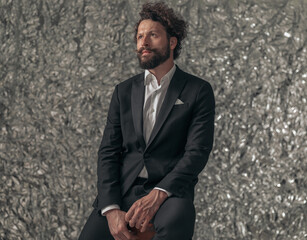 sexy elegant man with long beard wearing black tuxedo and looking up