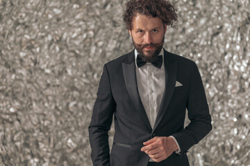 sexy young groom in black elegant tuxedo holding hands in pockets