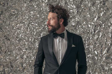 portrait of unshaved elegant groom in black tuxedo looking to side