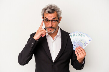 Middle age business man holding bills isolated on blue background  pointing temple with finger, thinking, focused on a task.