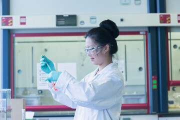 Female scientist in lab pipetting sample into lab beaker