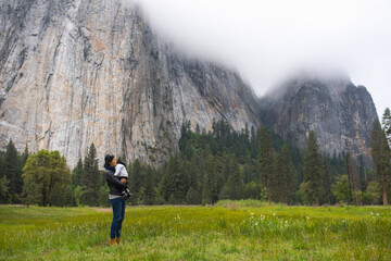 Mid adult woman carrying toddler daughter in meadow, Yosemite National Park, California, USA