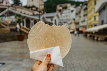  Famous Carlsbad wafer,CZ: lazenske oplatky, originated in 1867. Woman hand holding traditional Czech sweet cookie snack made in Karlovy Vary, famous spa city on UNESCO list.Tasty food background © Eva