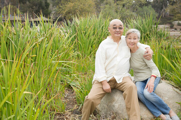 Fototapeta premium Portrait of senior couple sitting on rock