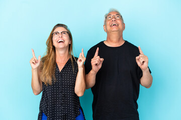 Middle age couple isolated on blue background pointing up with the index finger a great idea