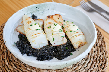 diner's view of a plate of grilled baby squid over black rice
