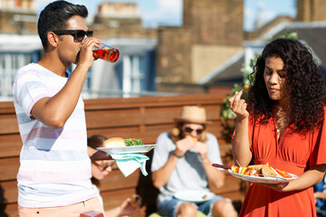 Friends eating party food and drinking at rooftop party