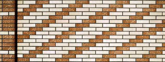 The wall of the building is lined with facing bricks or tiles. Beige and white bricks alternate and...