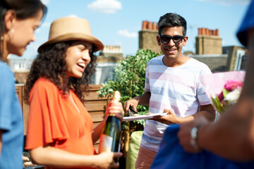 Female and male friends with champagne bottle at rooftop barbecue
