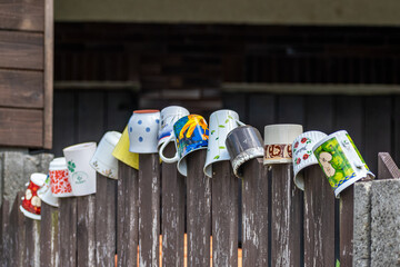 Selective focus shot of mugs on wooden planks of a fence