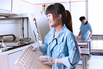Young woman in manufacturing plant making flexible electronics eyes closed laughing