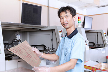 Young man holding sheet of flexible circuits, looking at camera smiling