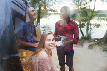Naklejka premium Friends chatting beside van by lake