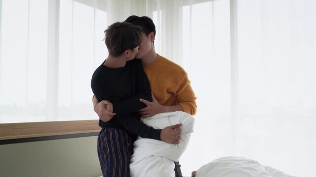 Gay lgbt couples are teasing each other in the bedroom, they hug and kiss each other relentlessly.
