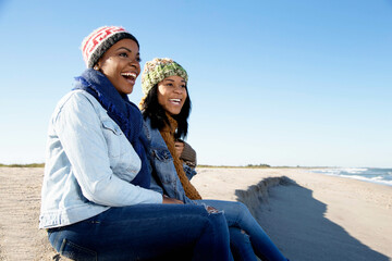 Two female friends relaxing at beach in winter