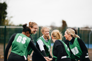 Female netball team shaking hands on netball court © Image Source Limited