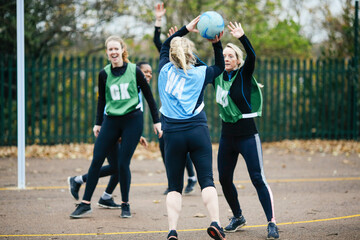 Female netball teams playing match on netball court - Powered by Adobe