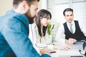 Obraz premium Young businesswoman and men looking at laptop in meeting