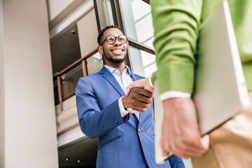 Low angle view of businessmen shaking hands outside office building © Image Source Limited