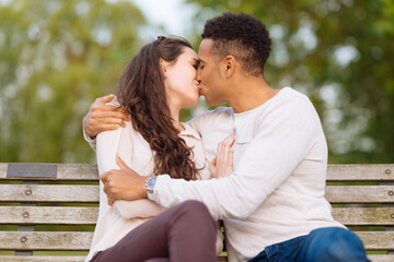 Obraz premium Young couple on park bench kissing