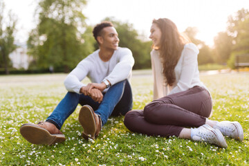 Young couple sitting on grass face to face smiling