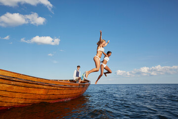 Women jumping from boat into ocean