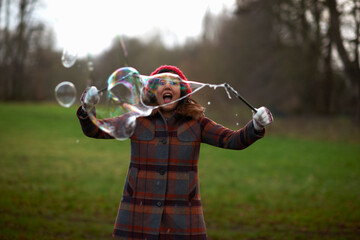 Woman in park using bubble wand to make bubbles