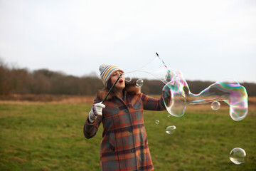 Woman in field using bubble wands to make bubbles
