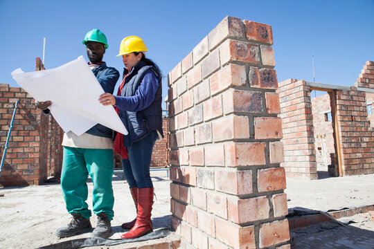 Site manager and builder looking at blueprint on construction site