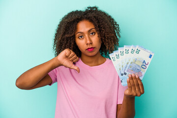 Young african american woman holding euro banknotes isolated on blue background showing a dislike gesture, thumbs down. Disagreement concept.