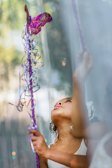 Young girl dressed as fairy, holding wand, playing outdoors