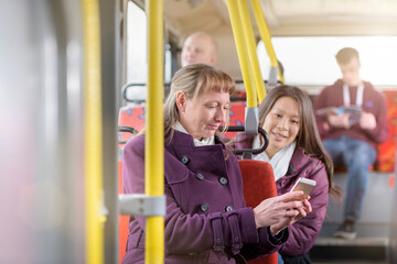 Passengers looking at smartphone on electric bus - obrazy, fototapety, plakaty
