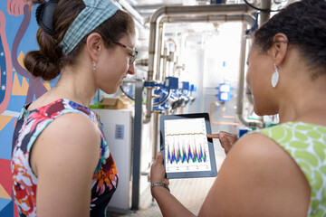 Community workers using digital tablet app to check heat pump energy