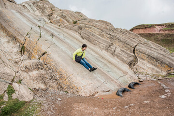 Woman sliding down rock slide, Sacsayhuaman, Cusco, Peru, South America