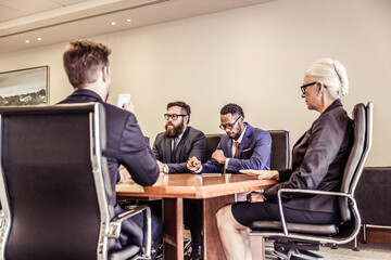 Mature businesswoman at conference table meeting with businessmen