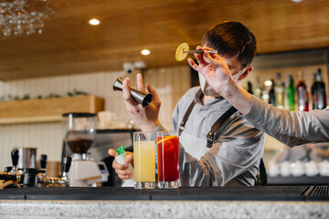 Two stylish bartenders in masks and uniforms during the pandemic, preparing cocktails. The work of restaurants and cafes during the pandemic.