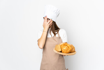 Young woman in chef uniform isolated on white background covering eyes and looking through fingers