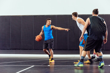 Male basketball player holding ball and pointing in basketball practice