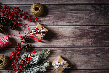Christmas holiday background with decor, gift, berries, cones, branches on dark wooden background. Festive holiday composition. Merry Christmas. Holiday greetings. Empty space for text. Copy space.