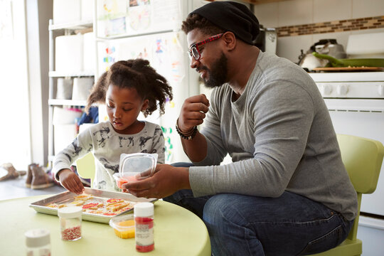 Father and daughter decorating unbaked cookies