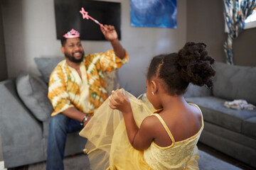 Man casting spell on daughter in fairy costume in living room