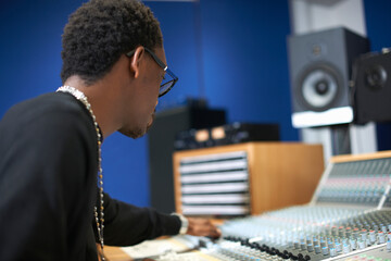 Young male college student at sound mixer in recording studio