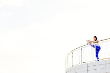 Fototapeta na wymiar Young woman exercising outdoors, stretching leg on railing, South Point Park, Miami Beach, Florida, USA