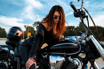 Sexy young woman sitting on motorcycle and having flirty look towards camera  - obrazy, fototapety, plakaty